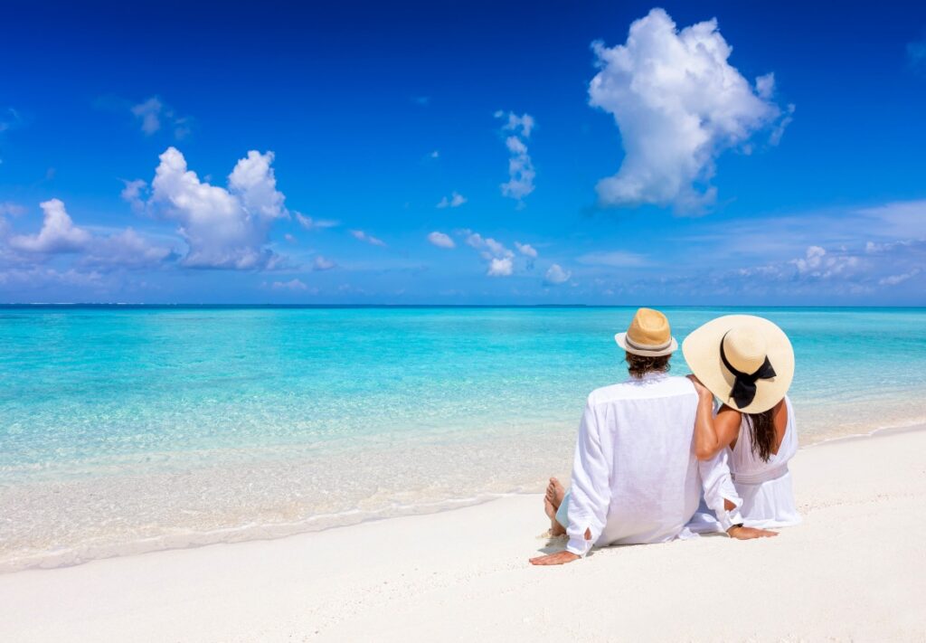 A tourist couple enjoys the view to the turquoise sea during their summer holiday